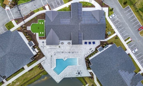 Aerial drone photo showing NOVO Avian Pointe's solar panel technology, pool deck and clubhouse